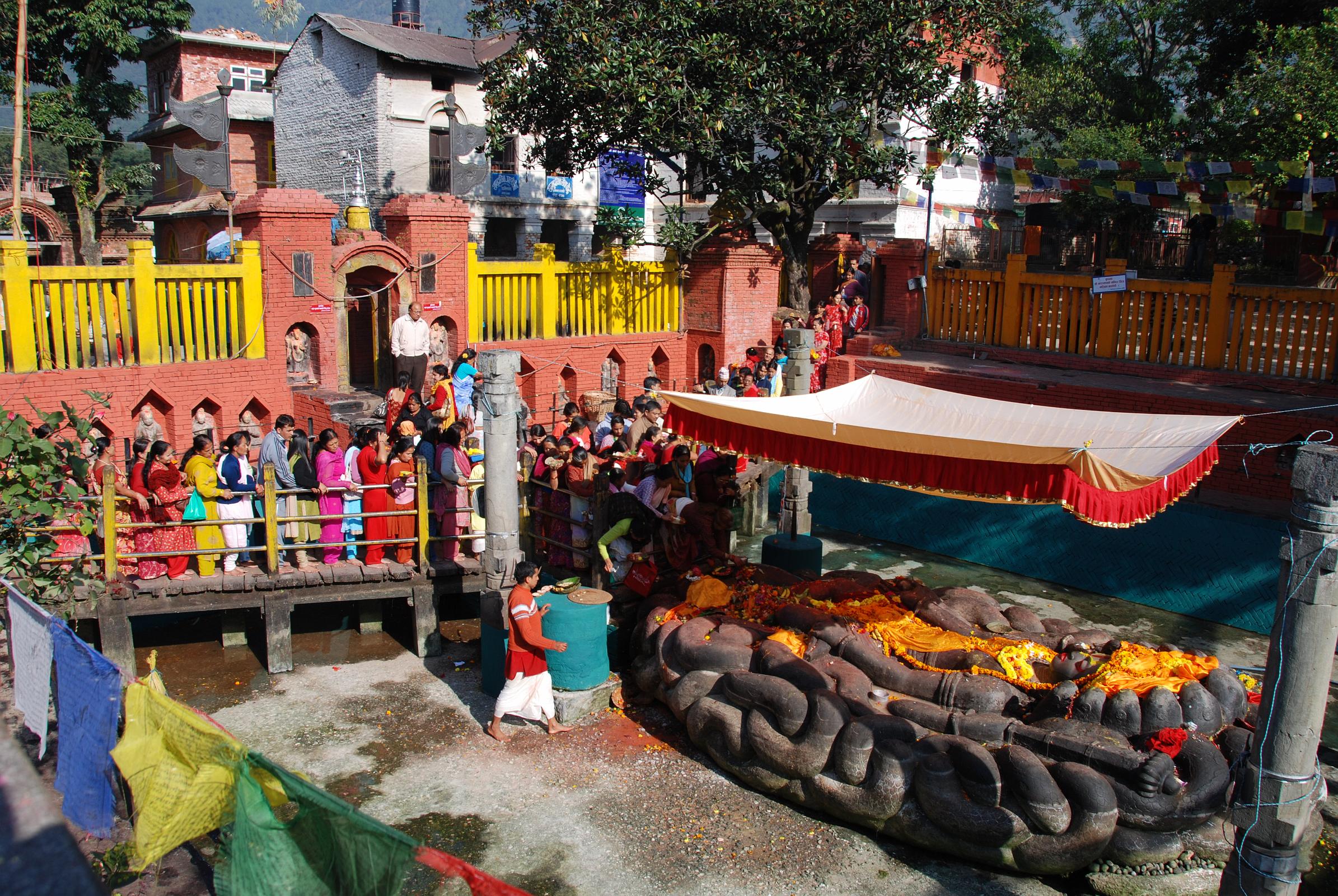 Kathmandu 09-1 Budhanikantha Pilgrims Near Sleeping Vishnu Statue Budhanilkantha Narayan (Sleeping Vishnu), 15km north from Thamel in Kathmandu, is a temple complex with a 5m long great stone figure of the Hindu god Vishnu reclining on the coils of the cosmic serpent Ananta, lying in a 13m long tank. It is believed that the deity was carved in the 7th or 8th century during the Licchavi period.